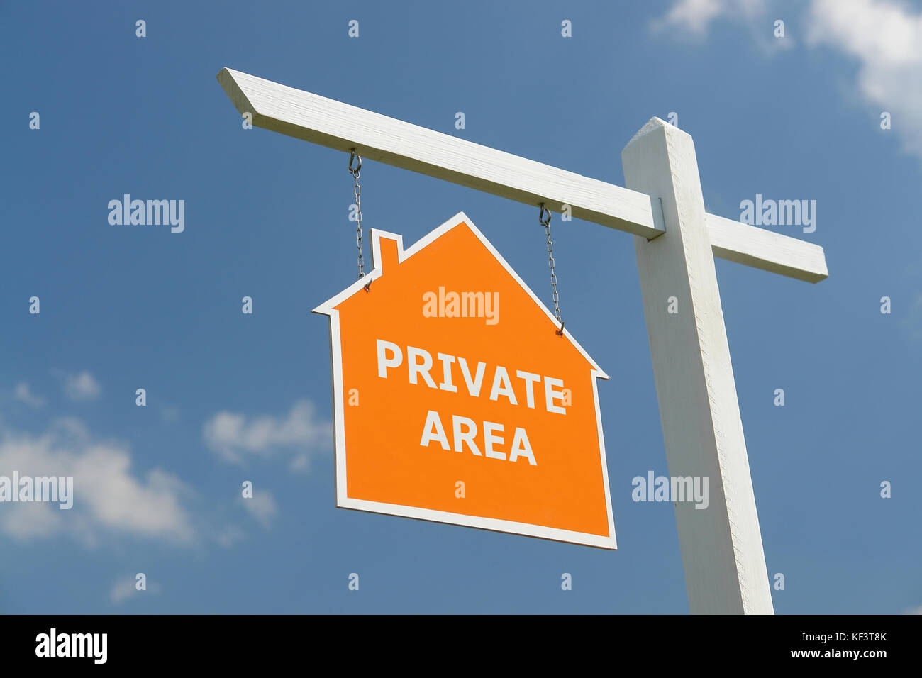 White wooden post with orange house-shaped notice board spelling Private Area - over blue sky Stock Photo