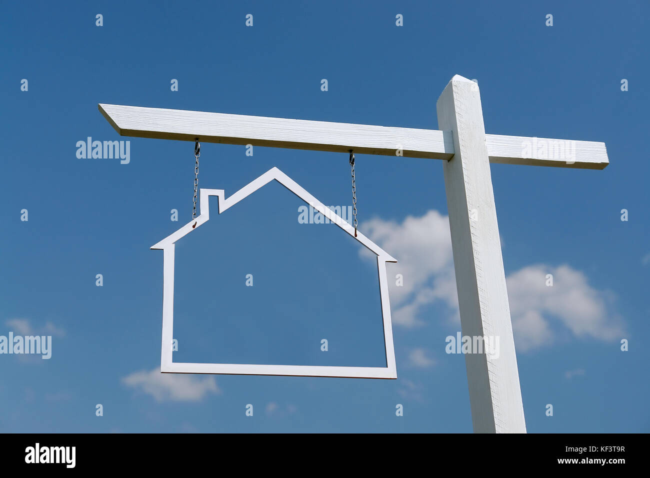 Wooden post with house-shaped frame hanging over blue sky Stock Photo