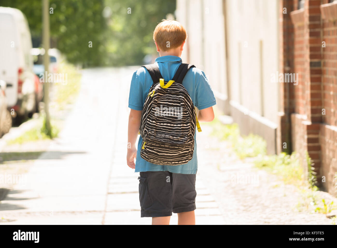 Rear View Of A Schoolboy With Backpack Walking On Sidewalk Stock Photo ...