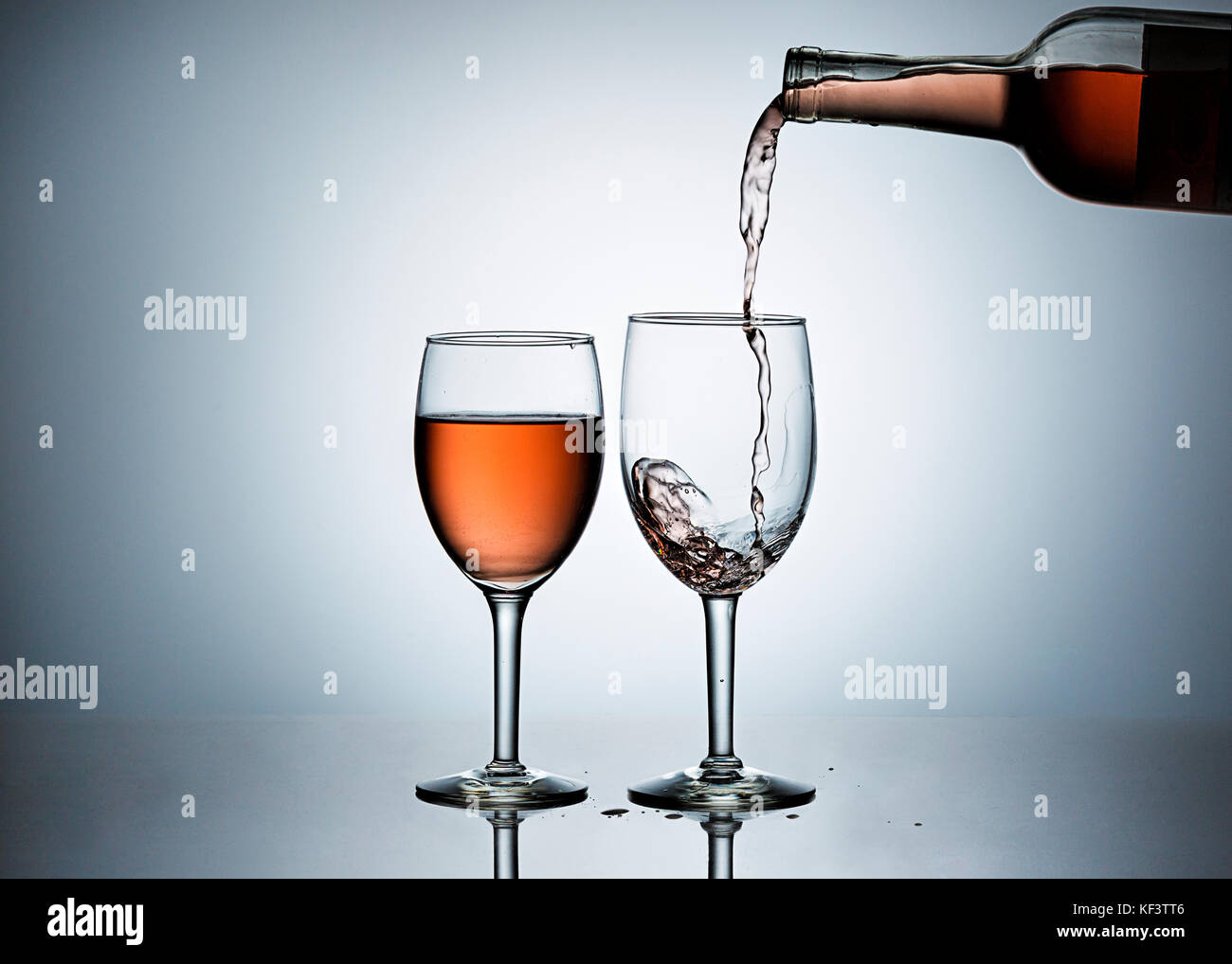 Pouring rose' wine form a bottle into wine glasses Stock Photo - Alamy