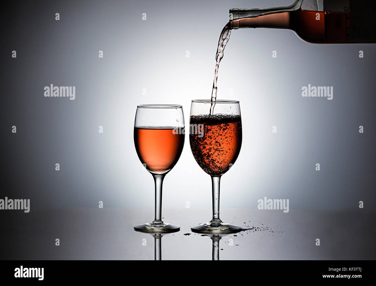 Pouring rose' wine form a bottle into wine glasses. Stock Photo