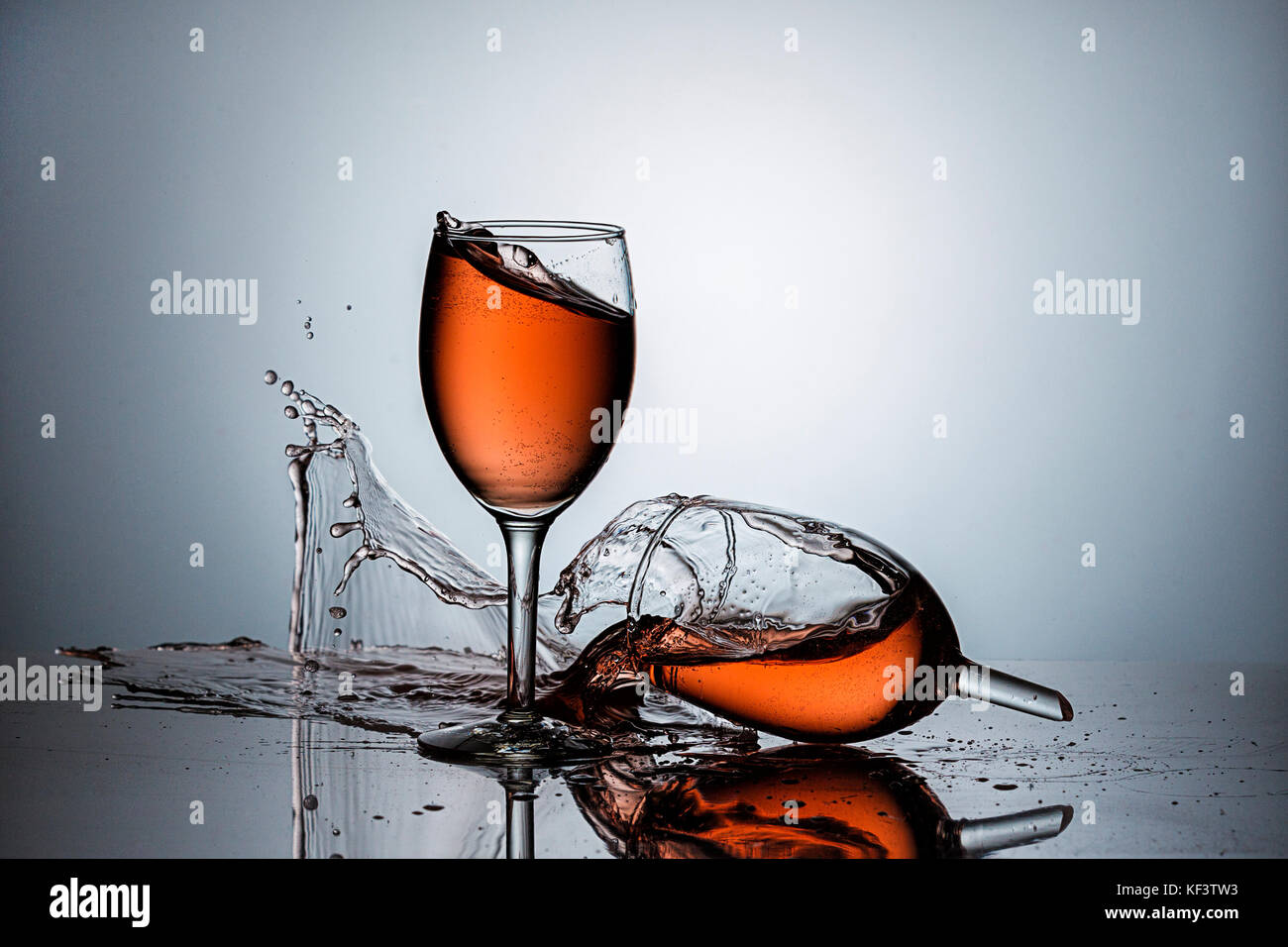 A broken wine glass spills wine after being dropped. Stock Photo