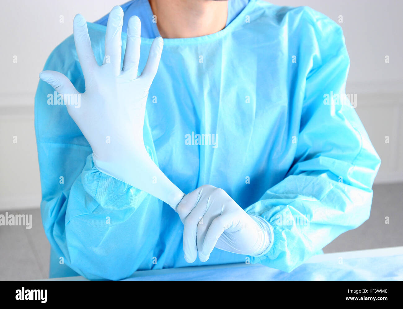 Doctor putting on sterile gloves isolated white Stock Photo