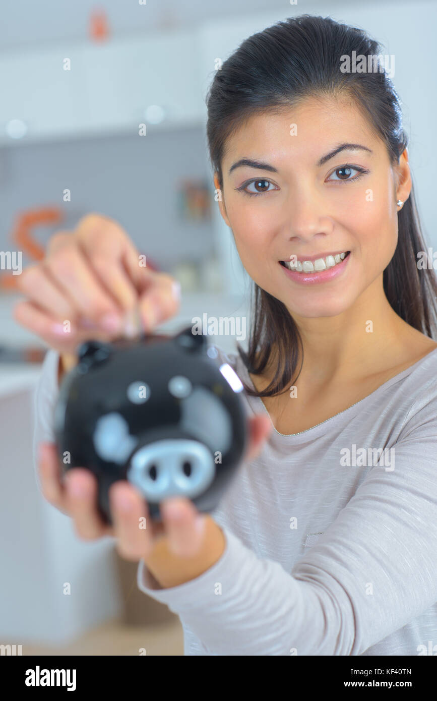 female hand putting coin into piggy bank closeup Stock Photo - Alamy