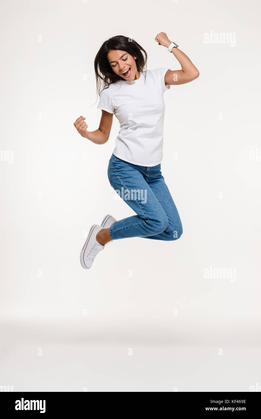 Full length portrait of a pretty joyful woman jumping isolated over ...