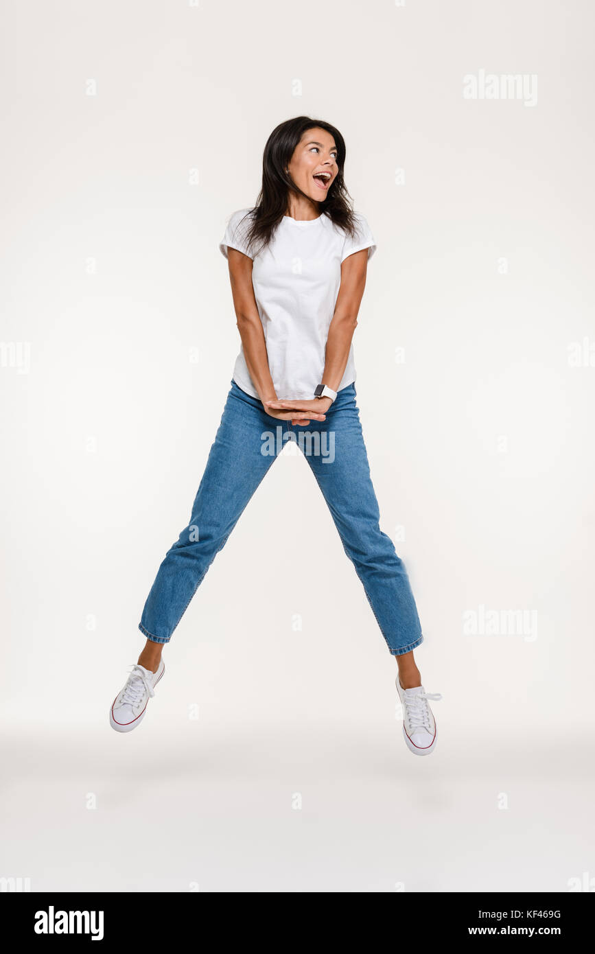 Full length portrait of a cheerful happy woman jumping and looking away ...