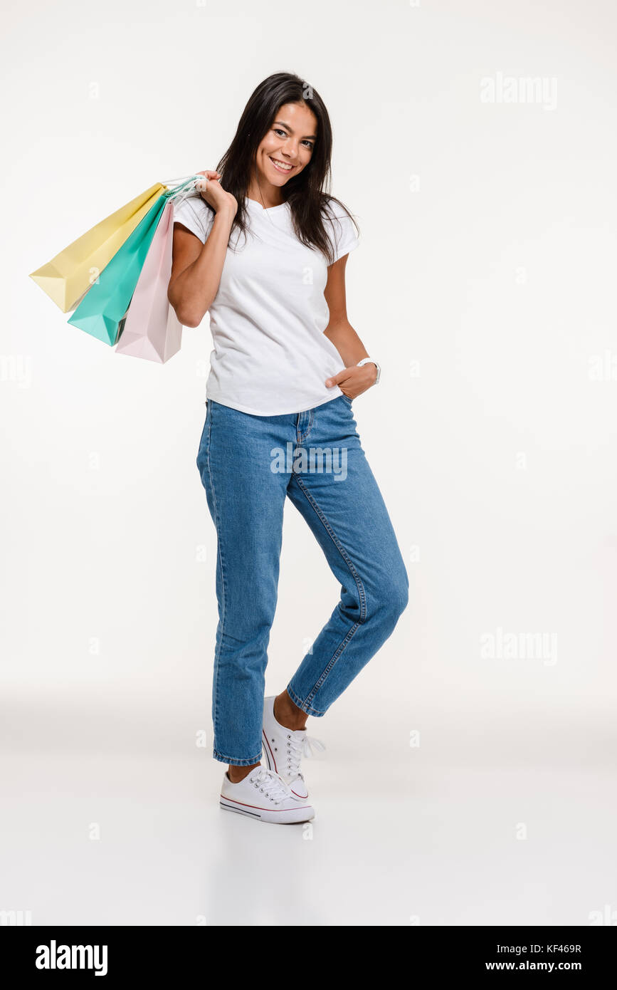 Full length portrait of a smiling young woman standing and holding ...