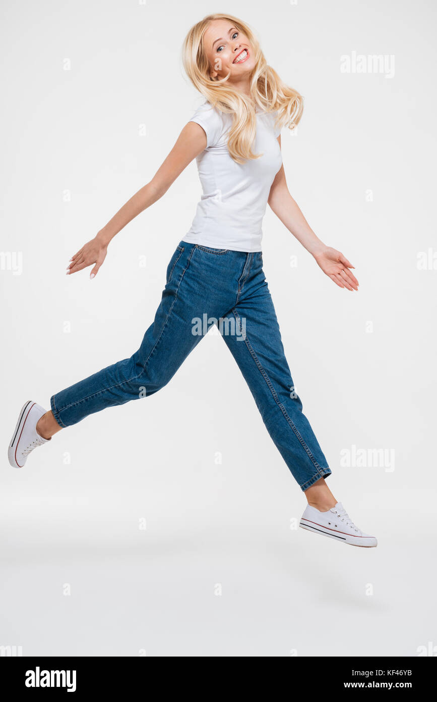 Full length portrait of a pretty joyful woman jumping isolated over ...