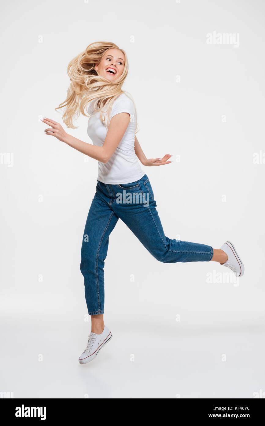 Full length portrait of a cheerful happy woman jumping and looking away ...