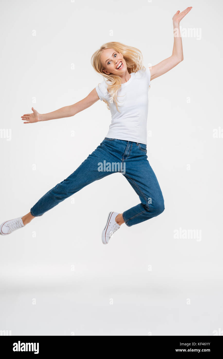 Full length portrait of a pretty happy woman jumping and looking at ...