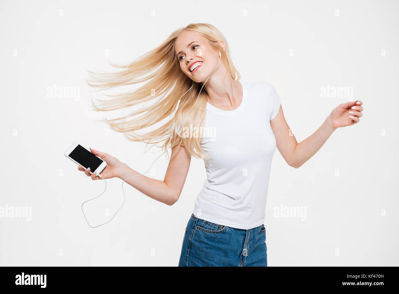 Portrait of a young smiling woman with long blonde hair listening music ...