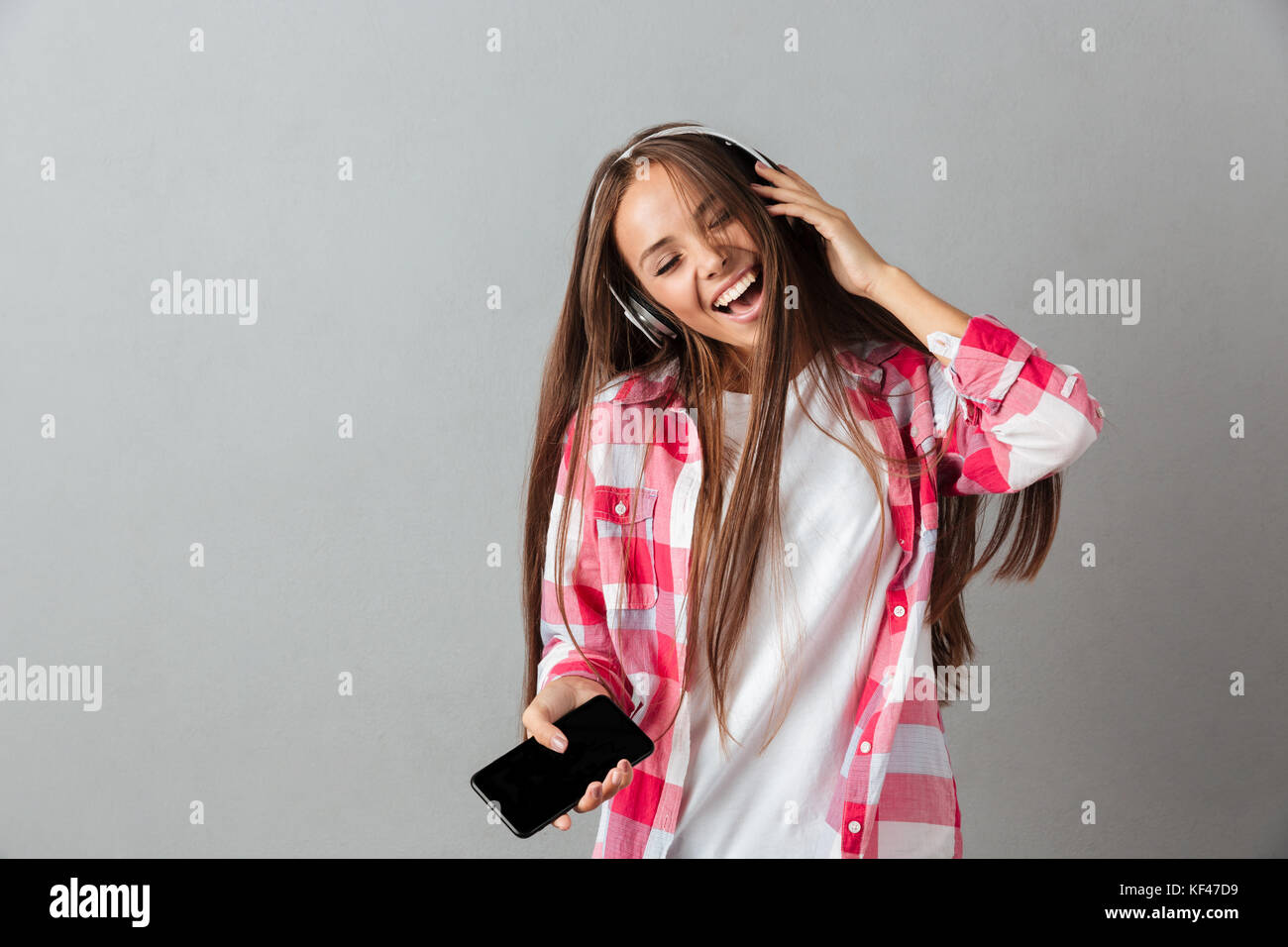Pretty young woman in headphones listening to music and singing with