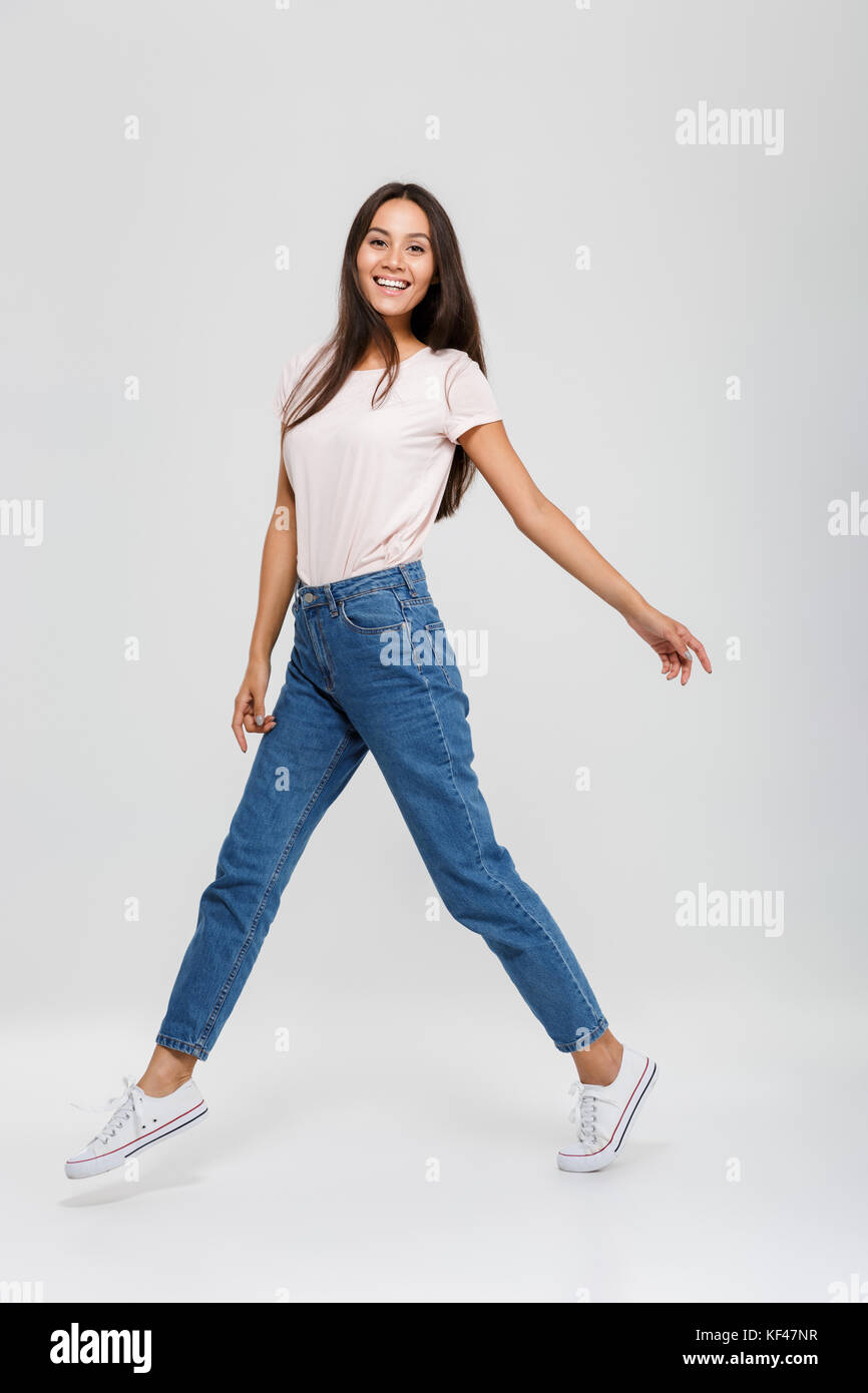 Full length portrait of a casual young asian woman jumping and looking ...