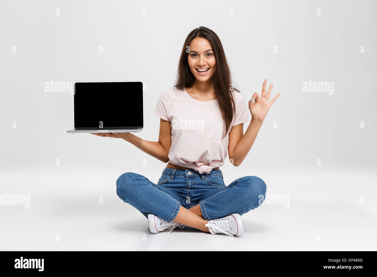 Portrait of a happy young asian girl holding blank screen laptop ...
