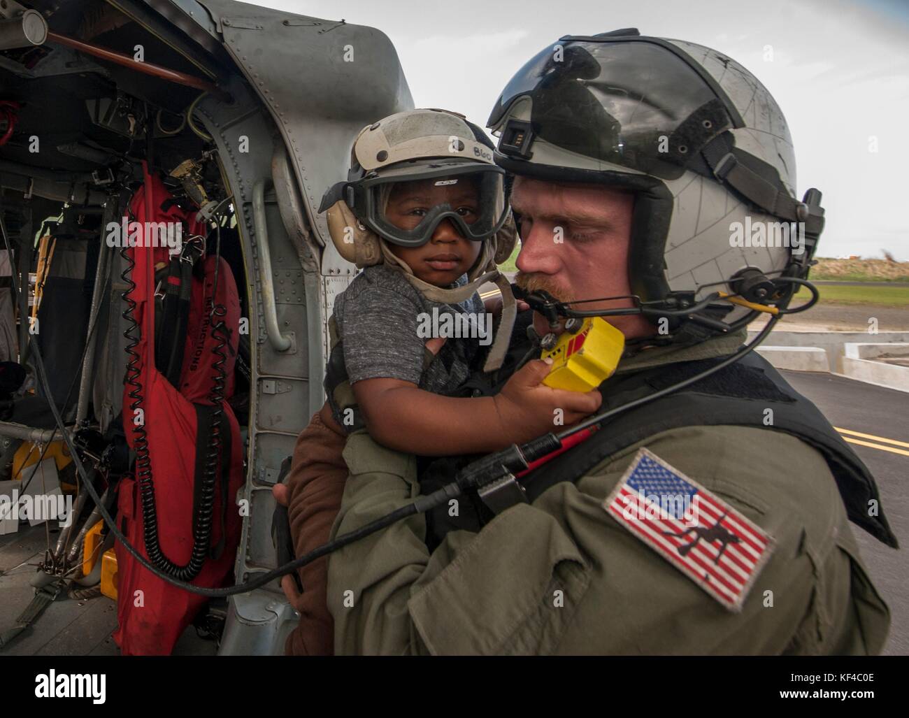 A U.S. Navy sailor evacuates a young boy in an MH-60S Seahawk helicopter following Hurricane Maria September 27, 2017 in Dominica. Stock Photo