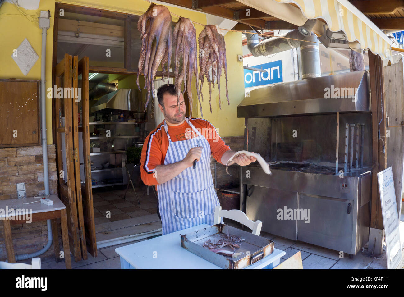 Local man clening a octopus at fish restaurant, harbour of Naxos-town, Naxos island, Cyclades, Aegean, Greece Stock Photo