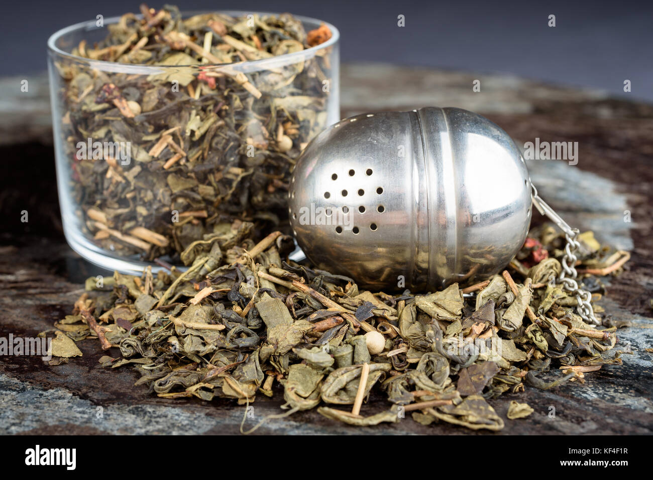 Green tea in and around glass jar with tea strainer. Stock Photo