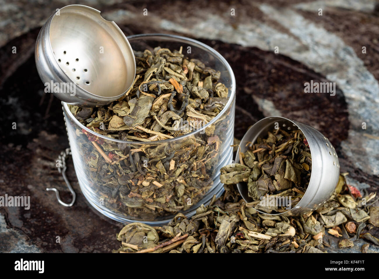 Green tea in and around glass jar with tea strainer. Stock Photo