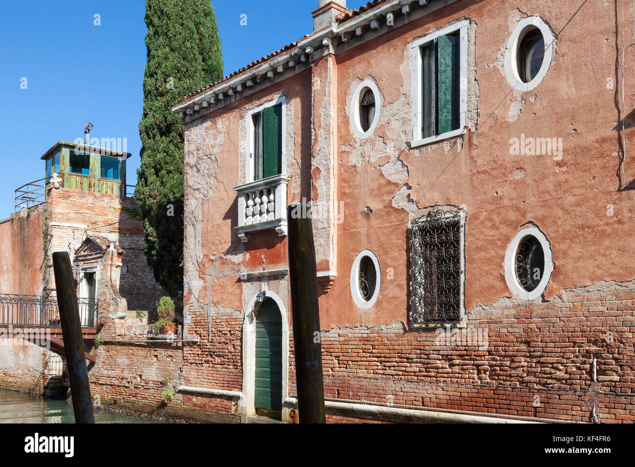Architectural detail of an ancient house, Giudecca, Venice, Italy  with lovely weathered red brick walls, peeling plaster  and round windows on a cana Stock Photo