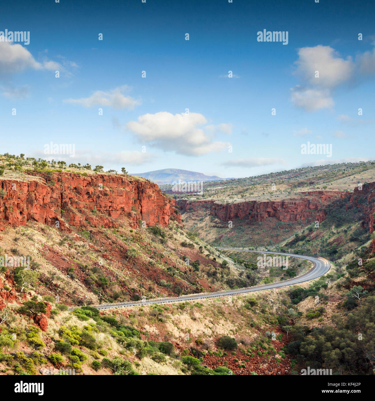 Magnificent red cliffs tower above a lonely road in the Pilbara region of Western Australia Stock Photo