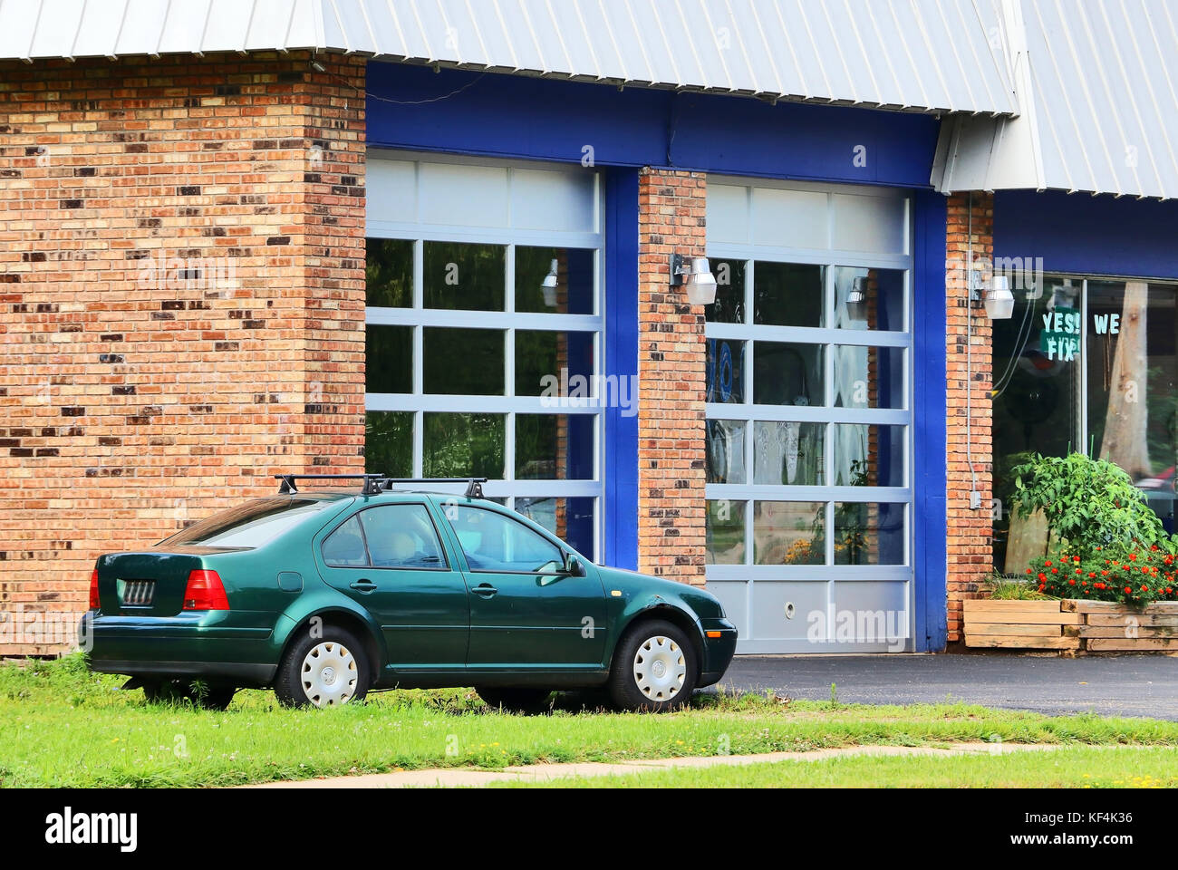 Parked car waiting for check up in front of small auto service shop. Car repair and service background. Stock Photo