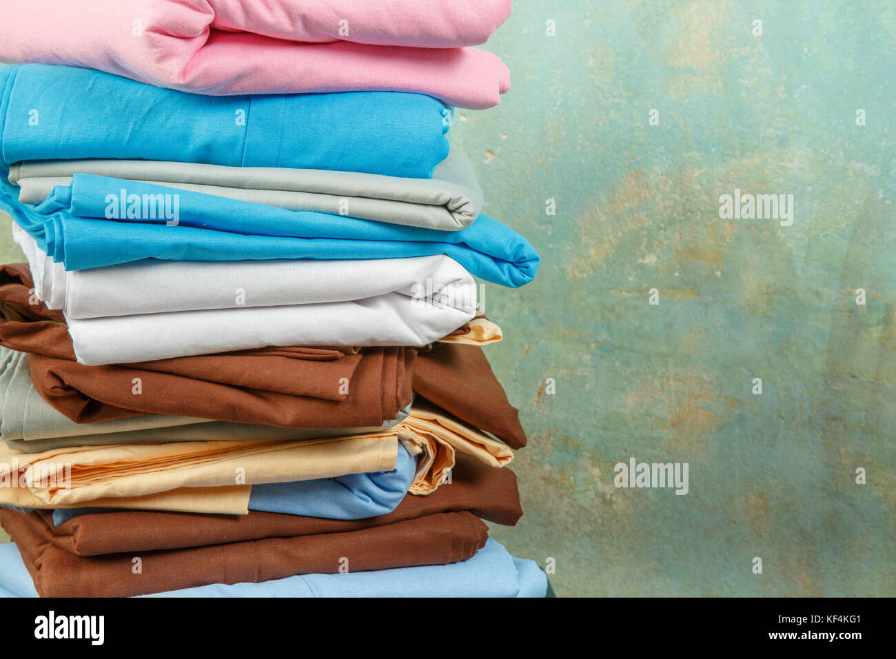 stacks colourful bed linen textiles clothing background pile concept. piles of bed linen Stock