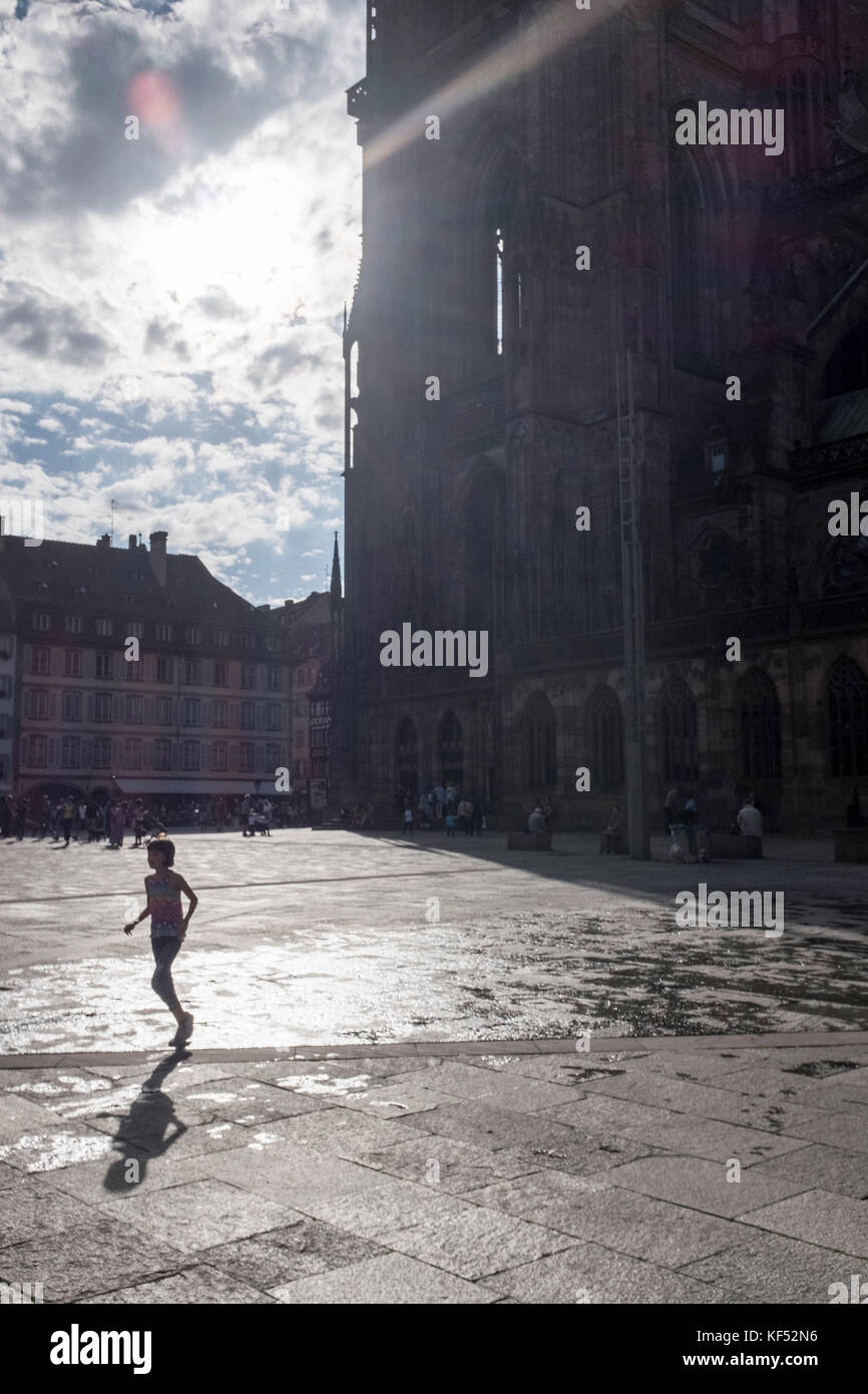 A girl runs across the square next to Strasbourg Cathedral, France Stock Photo