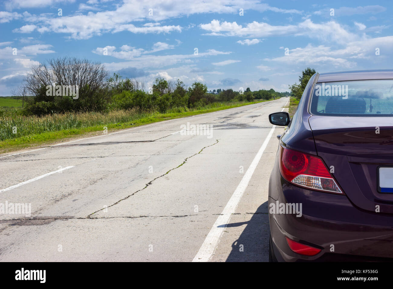 Rear view at the passenger car stopped in curb of asphalt road, copyspace Stock Photo