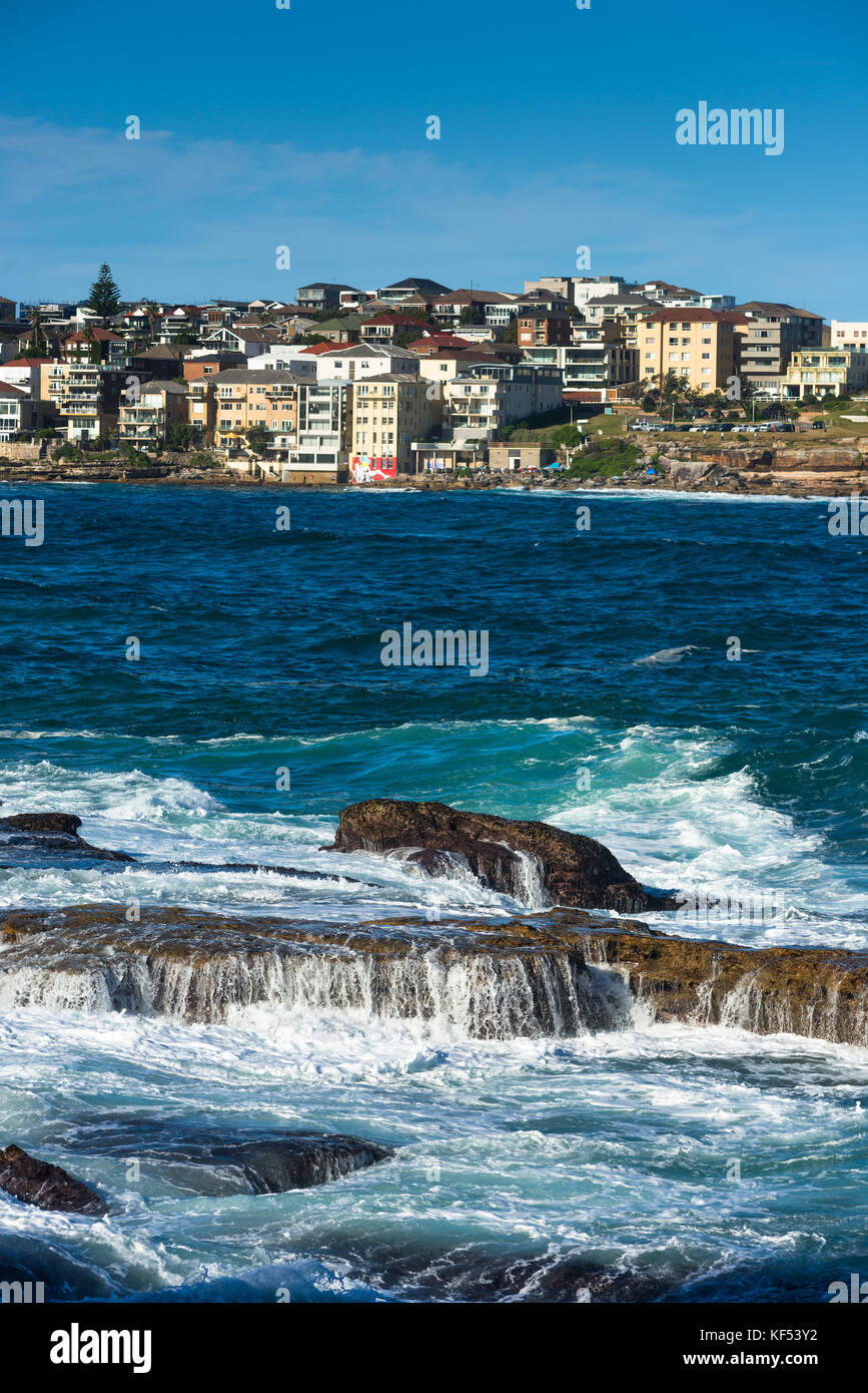 Waves hit the rocks with Bondi Beach in the distance. Sydney, New South Wales, Australia. Stock Photo