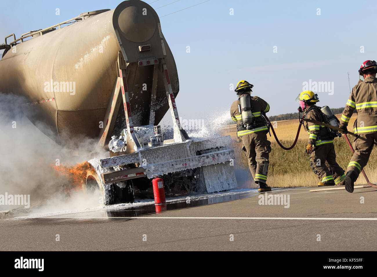 Three fireman rush to put out a brake fire on a semi-truck. Stock Photo