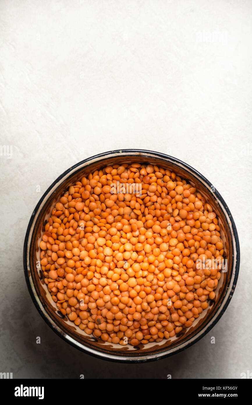 Red lentils in a clay plate on a cement background Stock Photo