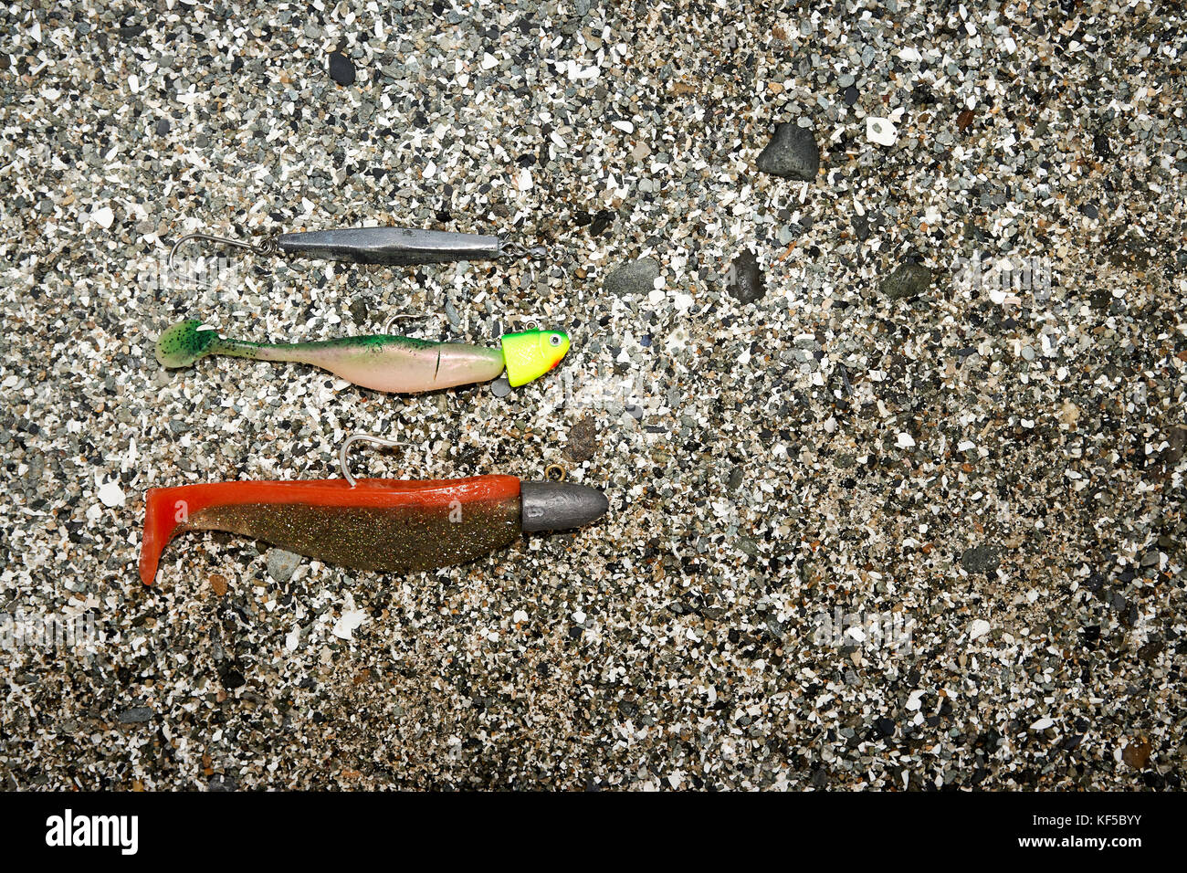 Different types of fishing baits lying against coarse-grained sand Stock Photo