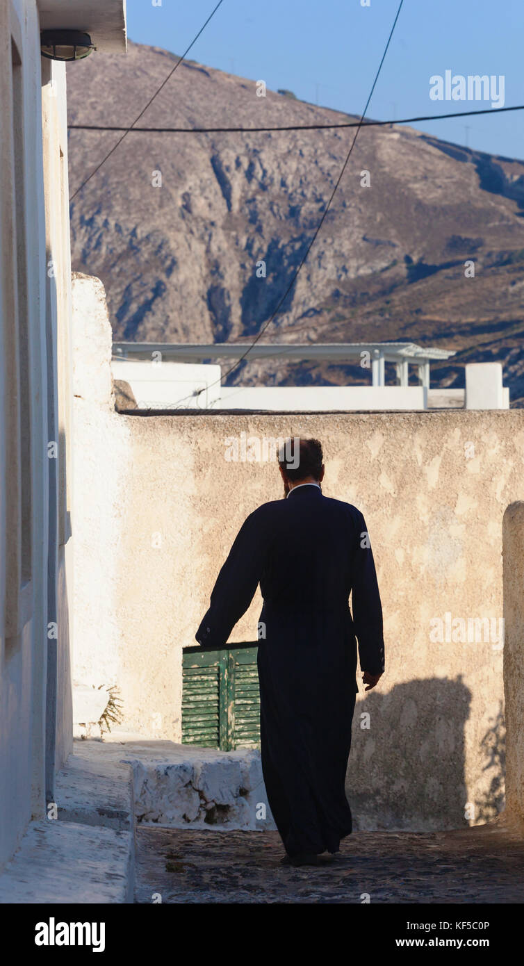 Santorini Island, Greece - July 19, 2012: Greek Orthodox priest walking in picturesque Pyrgos village. The island has more than 300 churches, two Orth Stock Photo