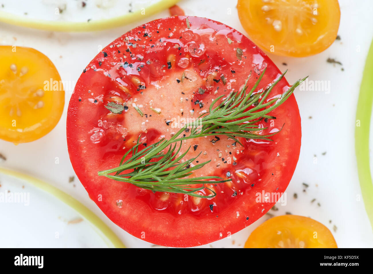 Round juicy slice of red tomato with herbs de Provence, sea salt and slices  of yellow tomatoes. The horizontal frame Stock Photo - Alamy