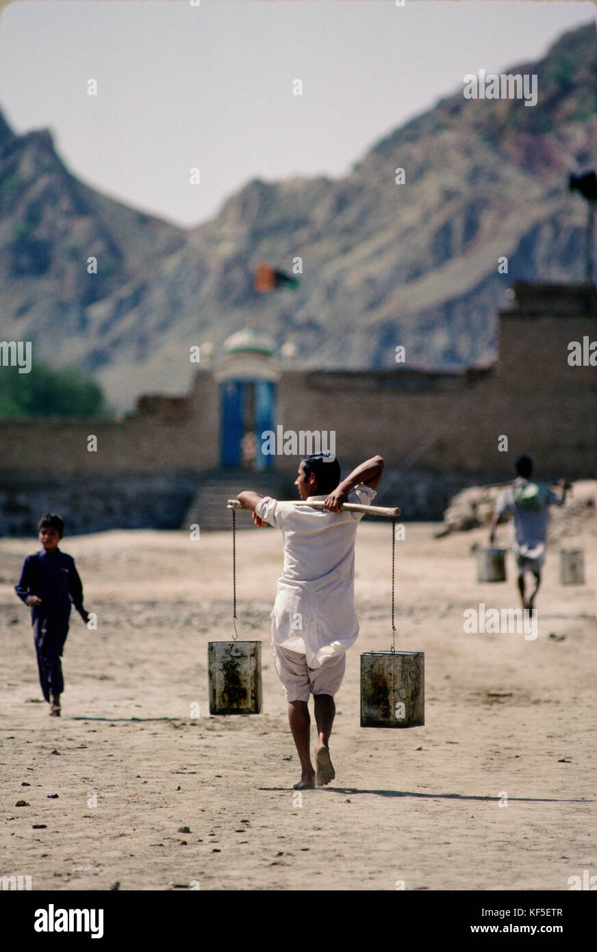People carrying water from the river Indus into Mari village near Kalabagh with the salt range in the background, Punjab, Pakistan. Stock Photo