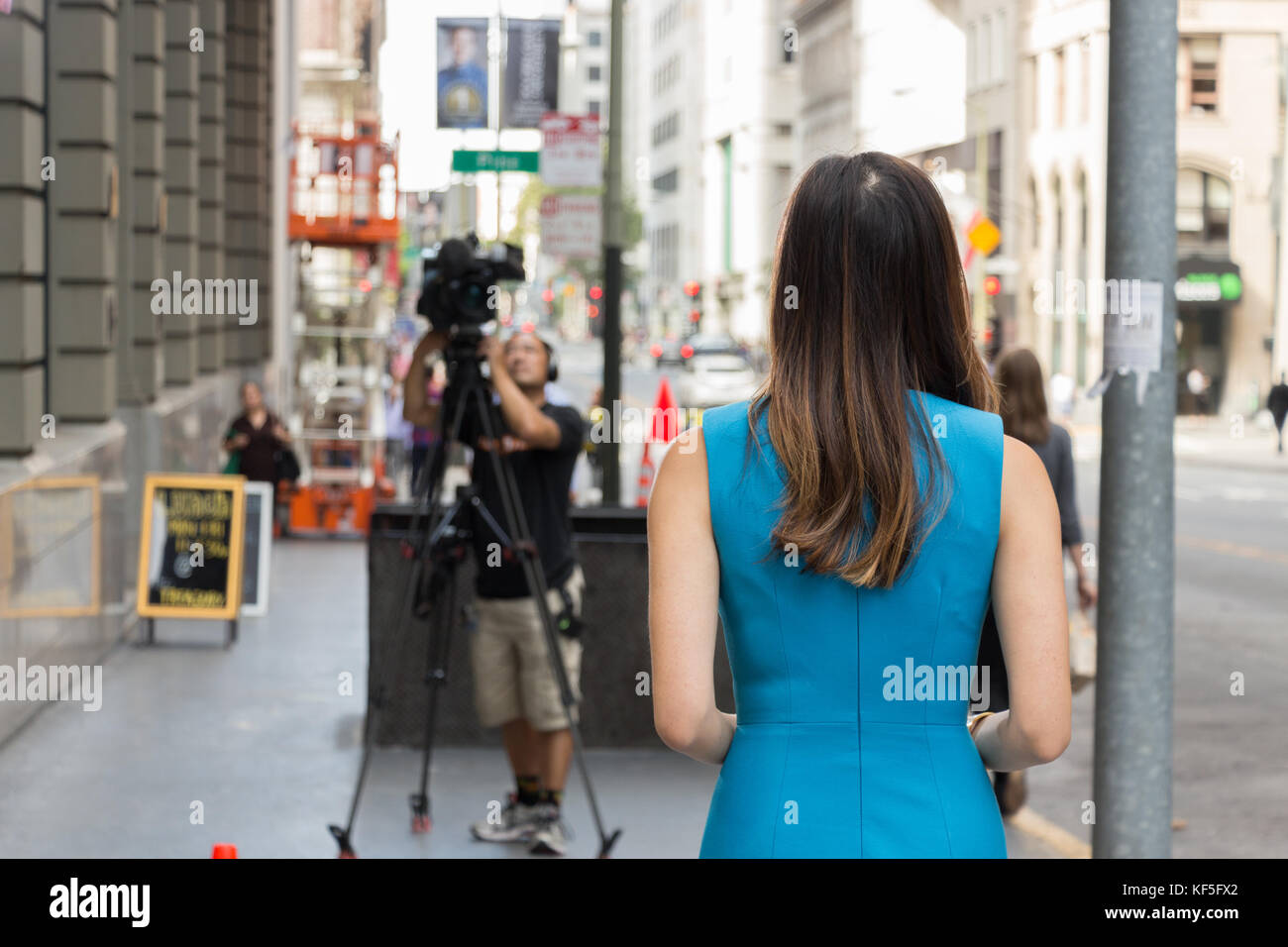 San Francisco, USA -  September 13th, 2017: An asian female TV reporter is looking ready to broadcast at a corner of the San Francisco downtown. Stock Photo