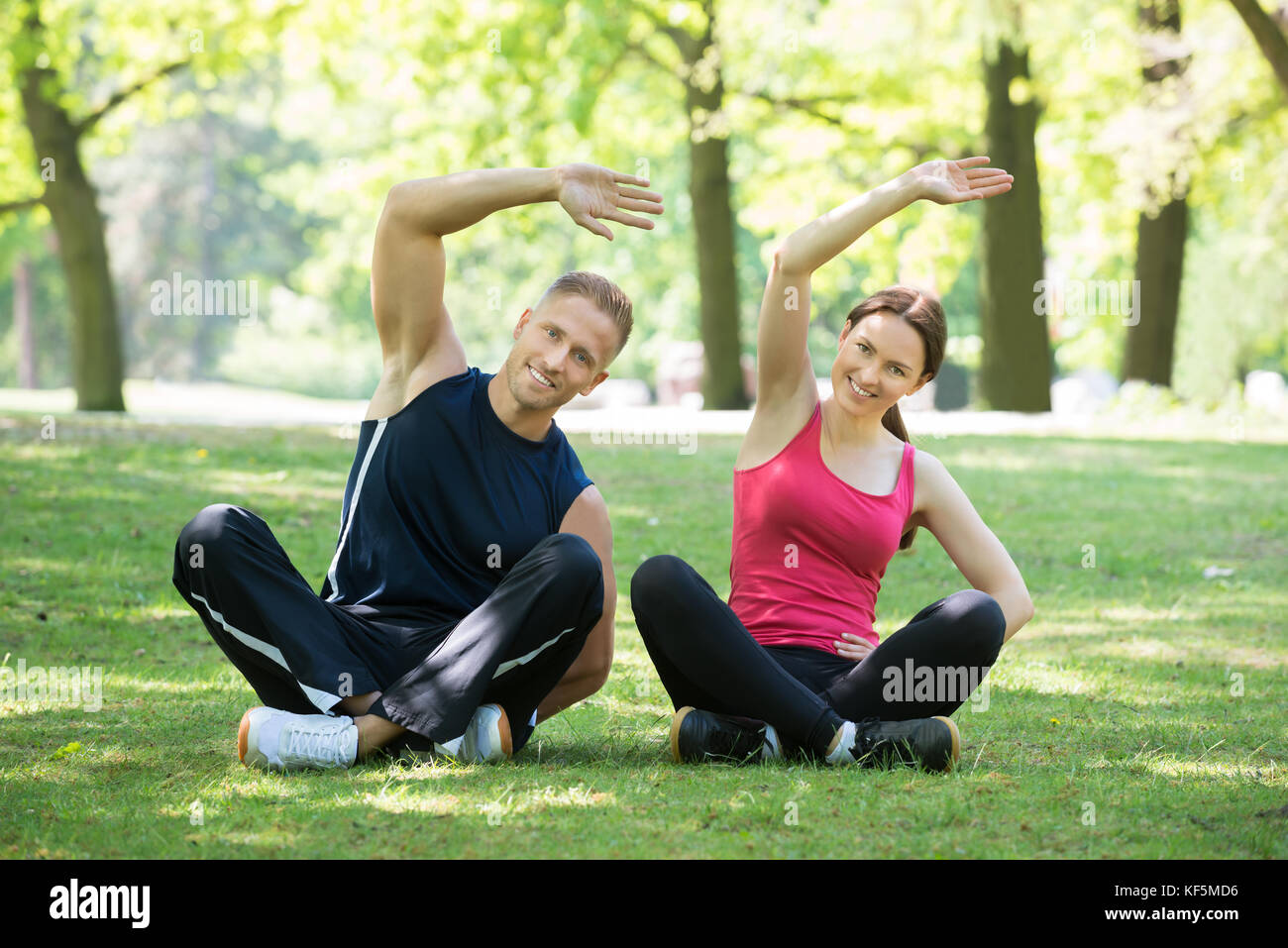 Happy Young Couple Doing Exercise In Park At Morning Stock Photo