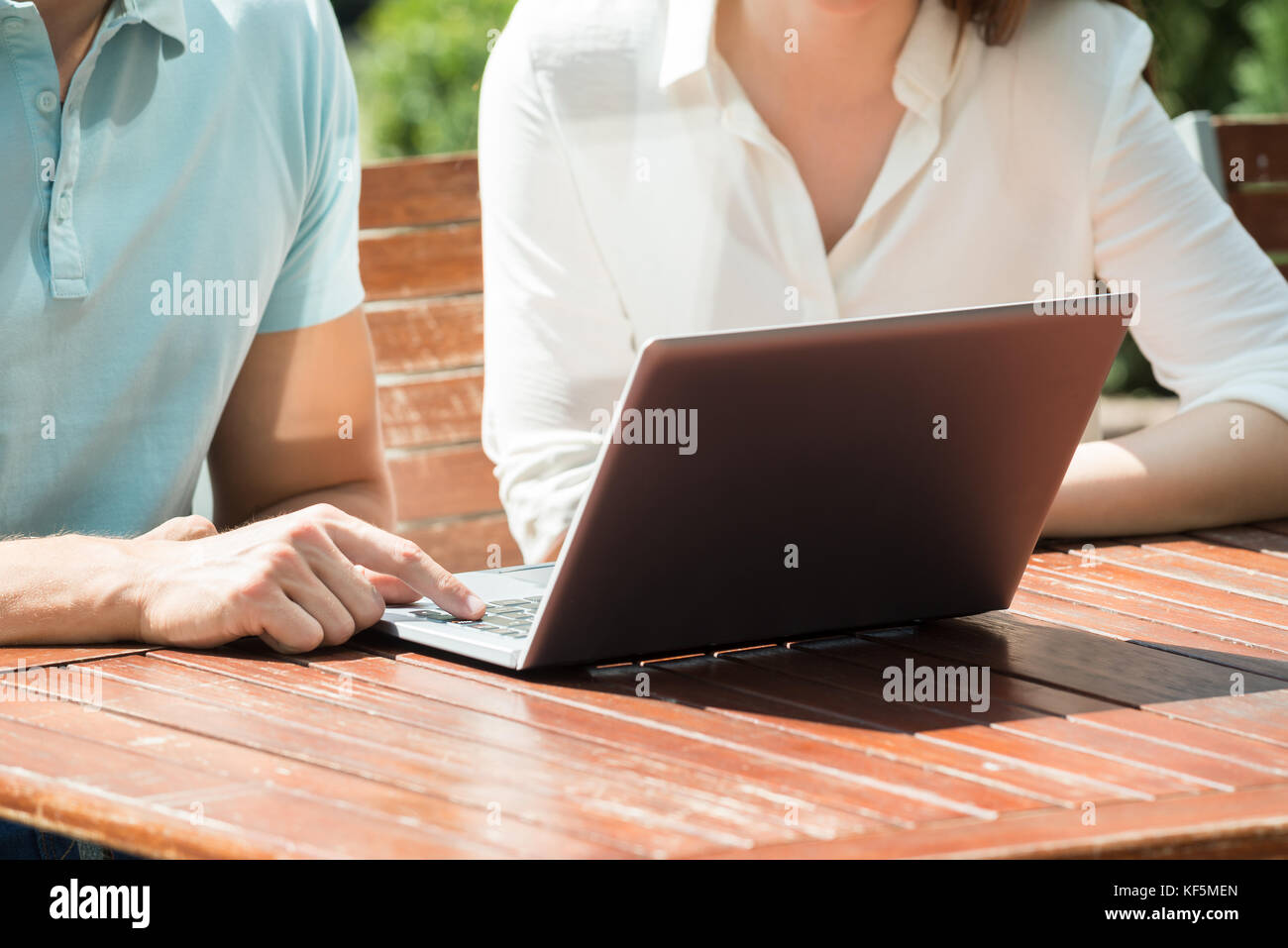 Close-up Of Couple Sitting On Bench Using Laptop Stock Photo - Alamy