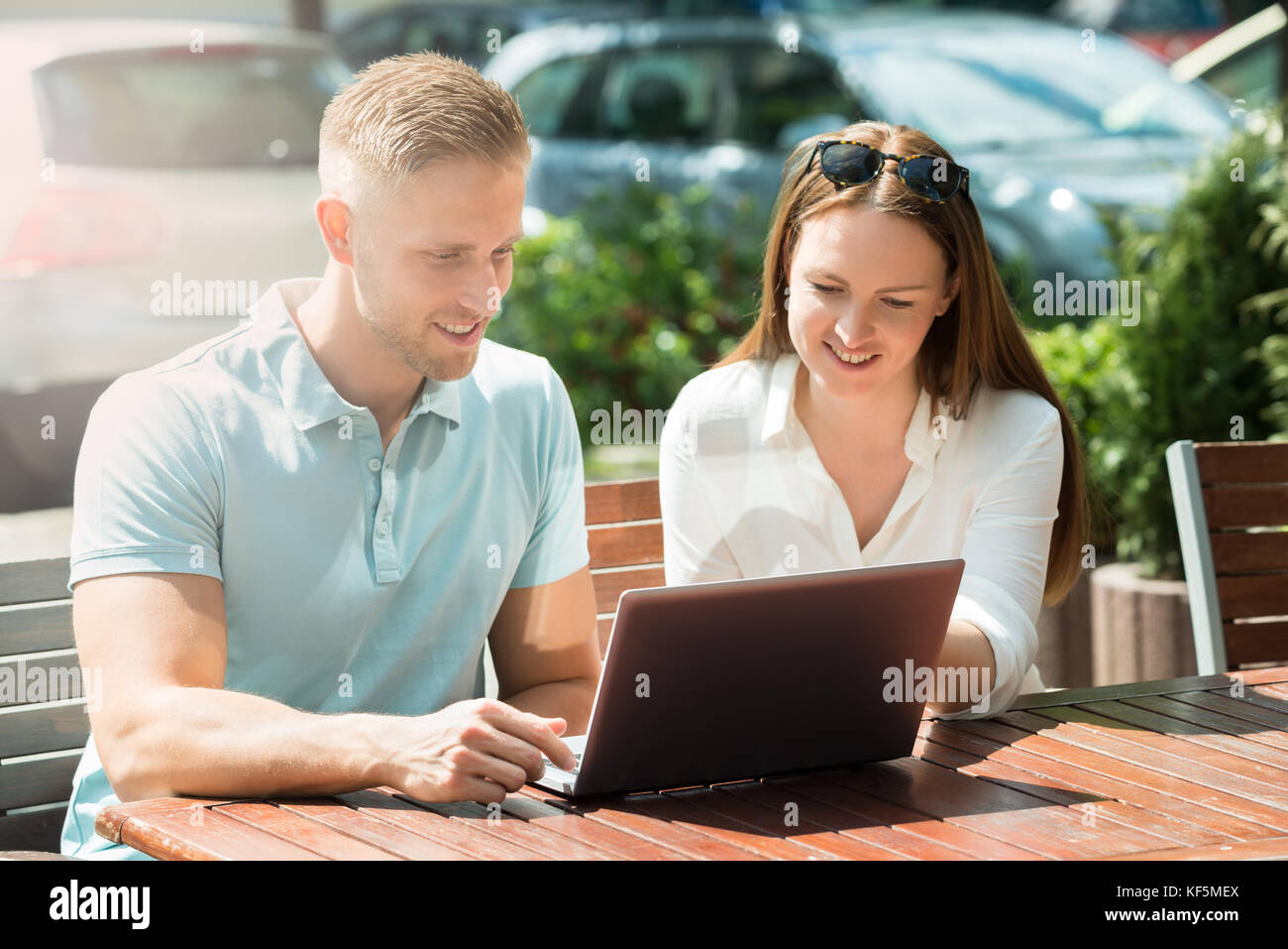 Young Couple Sitting On Bench Using Laptop Stock Photo - Alamy