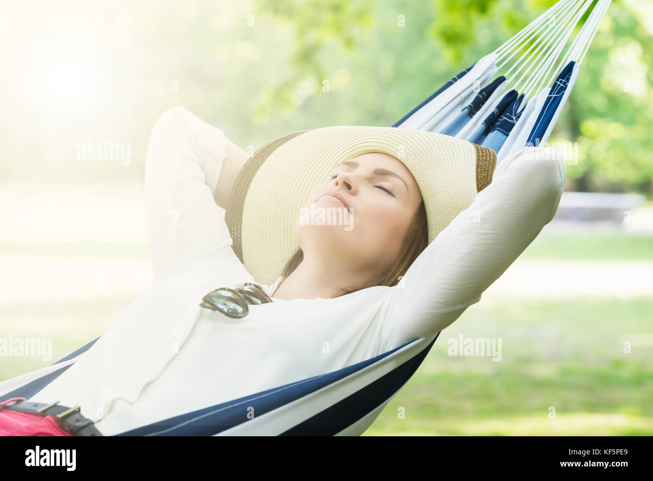 Young Woman Sleeping In Hammock At Park Stock Photo