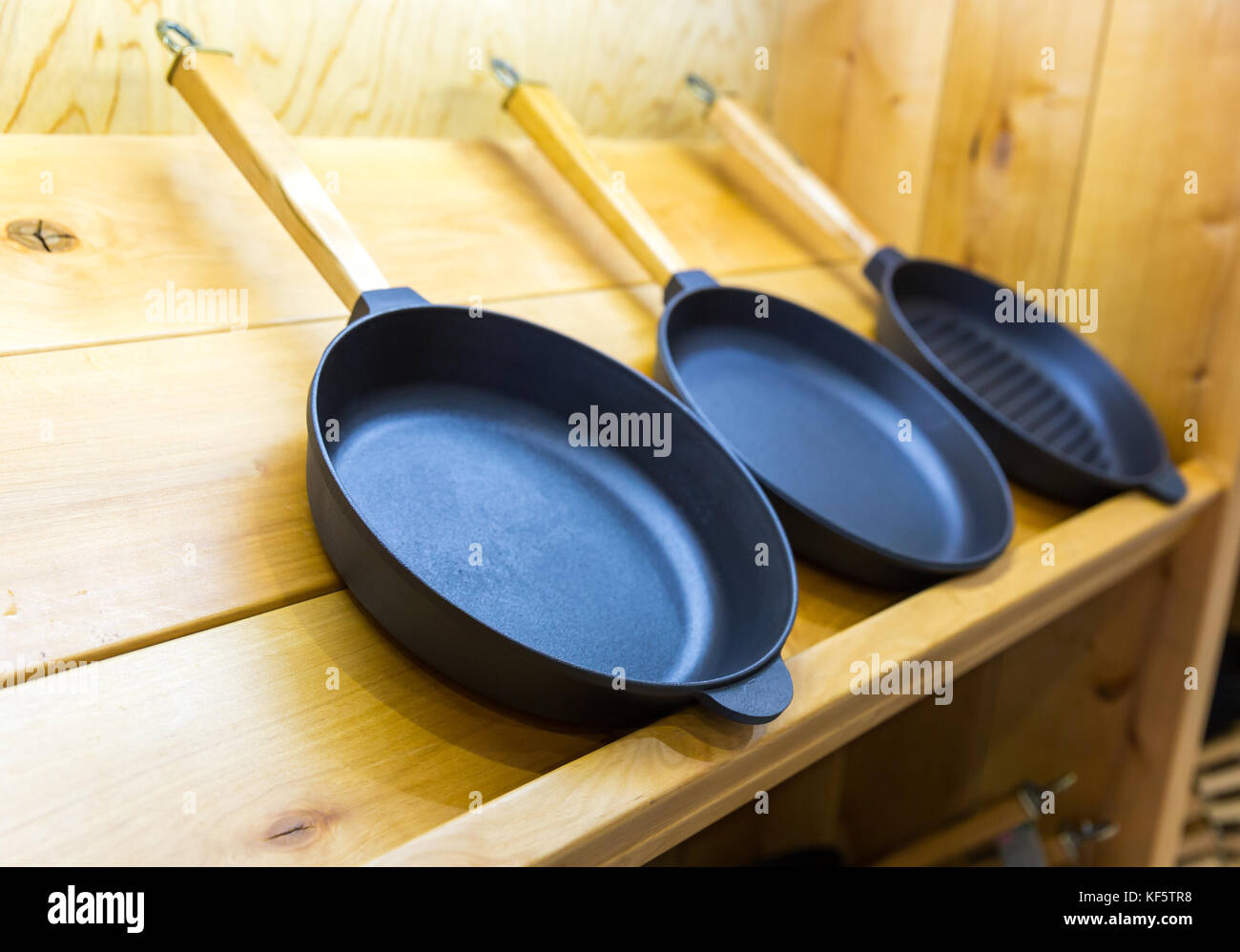 Frying pans on wooden shelf closeup Stock Photo Alamy