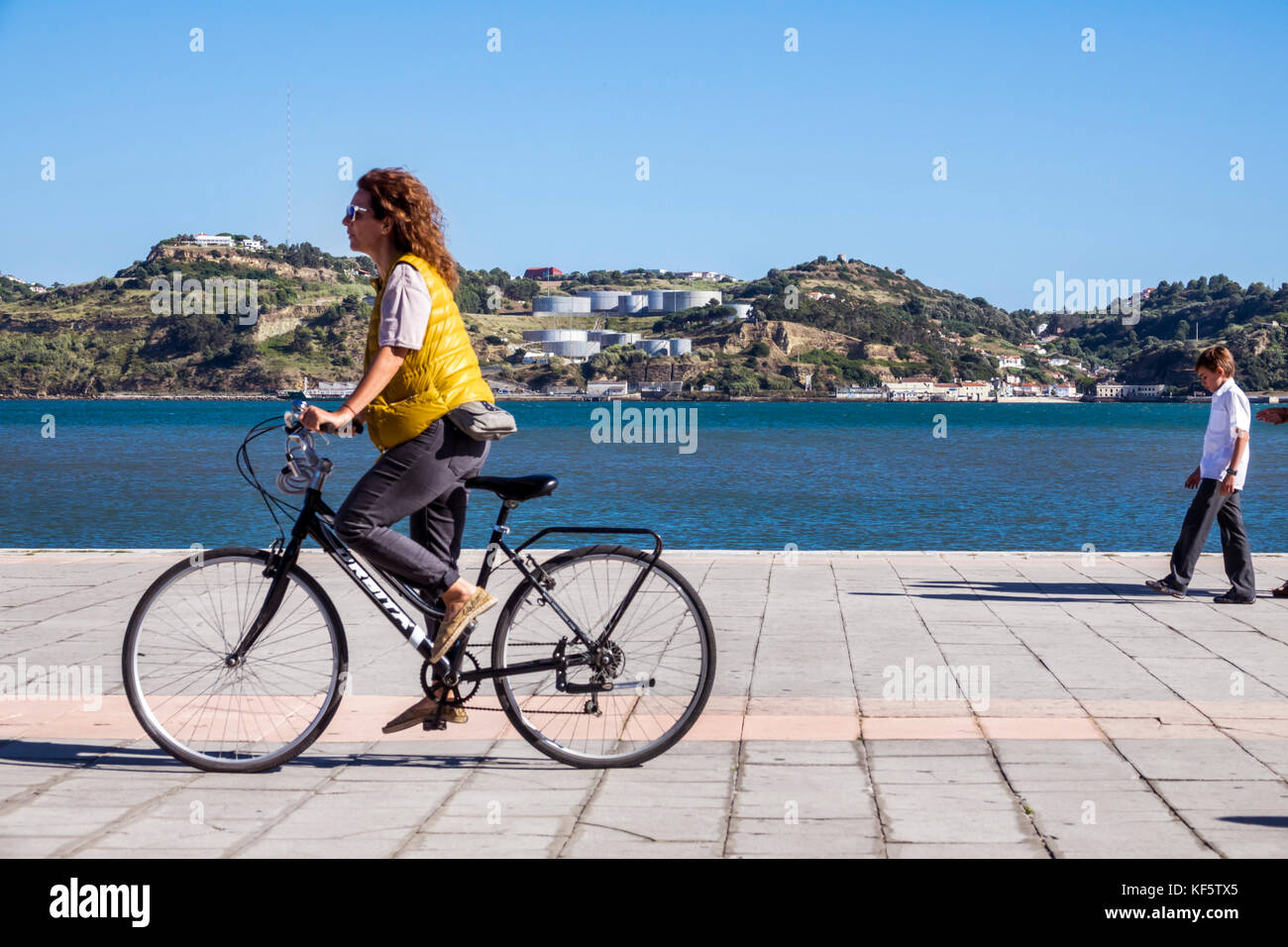 Lisbon Portugal,Belem,Tagus River,waterfront,promenade,woman female women,bicycle bicycles bicycling riding biking rider riders bike bikes,riding,view Stock Photo