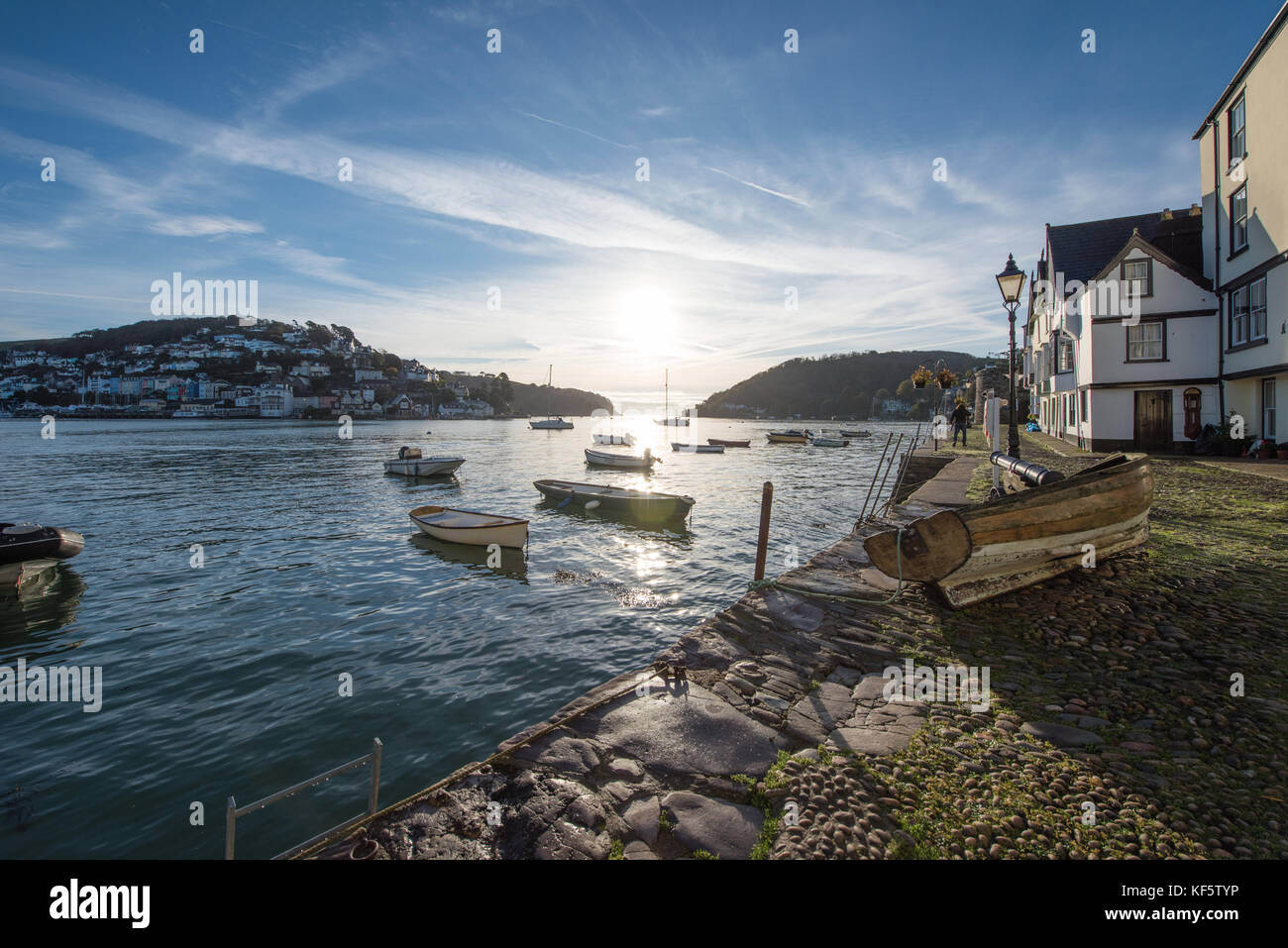 Beautiful early morning shot of Dartmouth fro Bayards Cove with a wooden boat on the quayside, and boats floating on the water with the sun rising Stock Photo