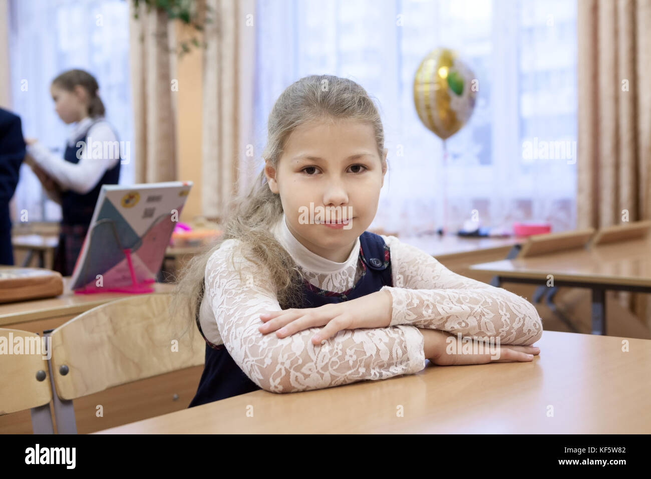 Portrait of Caucasian schoolgirl sitting at the desk in classroom and ...