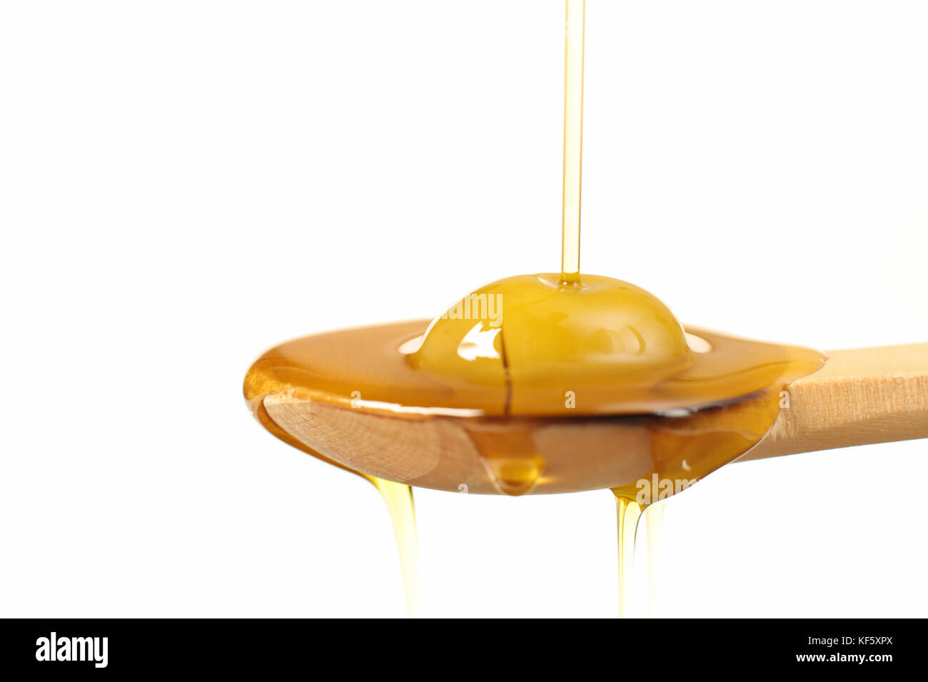 Close up view of virgin olive oil pouring on wooden spoon on white ...