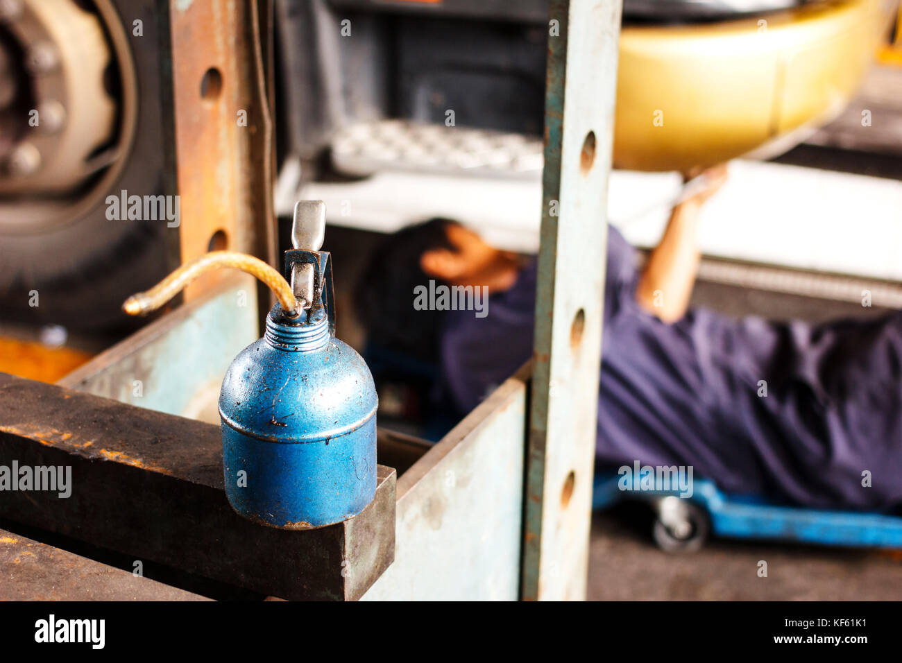 lubricant oil can and automobile mechanic checking truck in the garage, selective focus Stock Photo