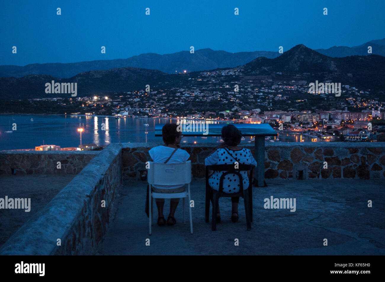 Corsica: old women enjoying the view of the night skyline of Ile-Rousse  (Red Island) seated on a chair on the top of Ile de la Pietra (Stone Island  Stock Photo - Alamy