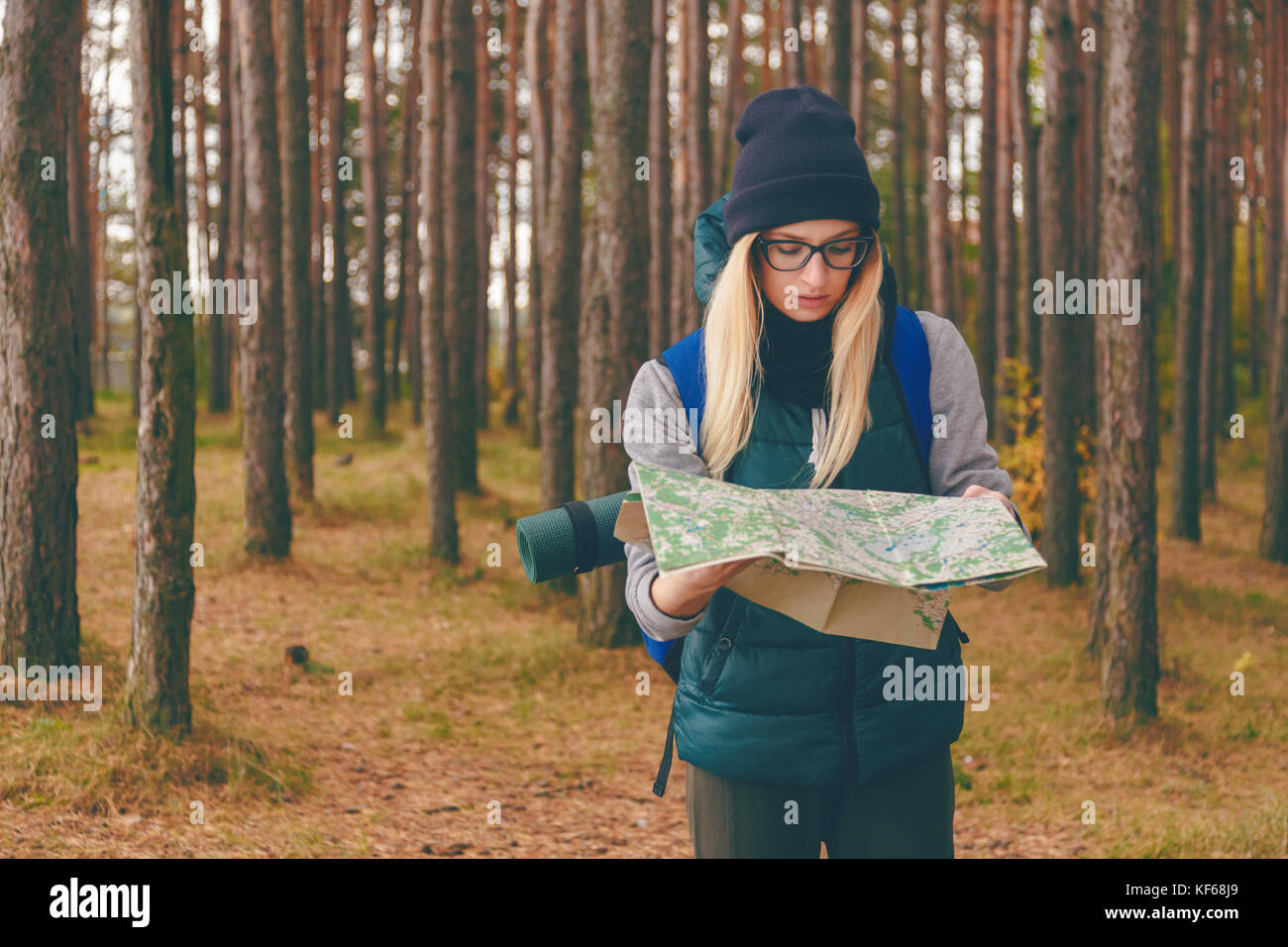 A beautiful young woman with travel map and backpack in pine forest Stock Photo