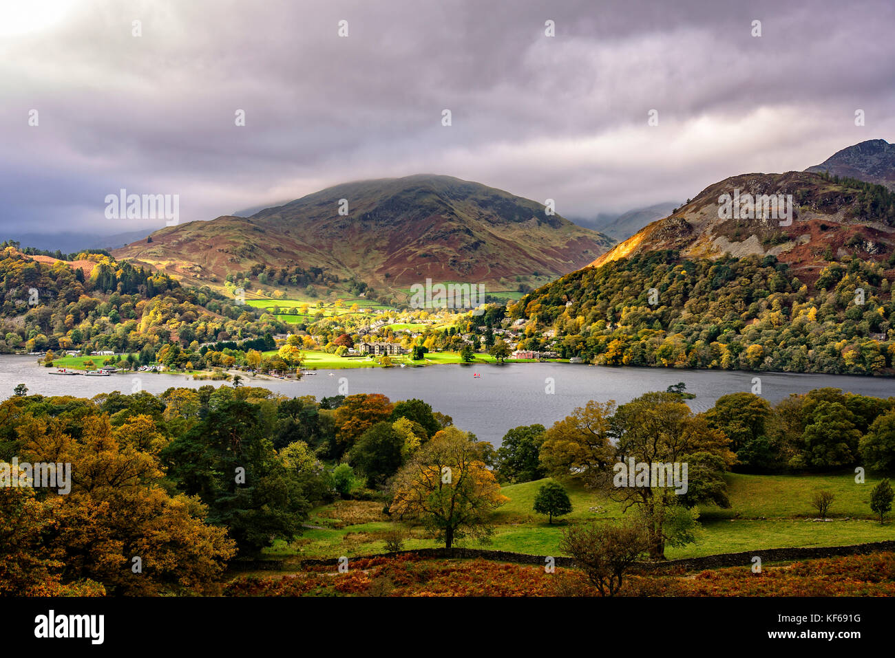 Looking across Ullswater to the sunlit village of Glenridding Stock Photo