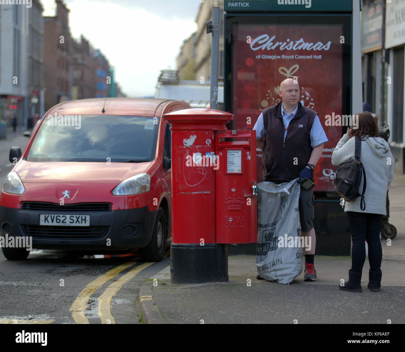 Royal Mail postman collecting letters street red postbox van talking to customer christmas poster Stock Photo